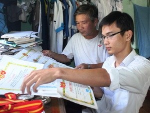 Thủ khoa Trần Hữu Chí và bố bên những tấm giấy khen mà Chí giành được trong 12 năm học phổ thông